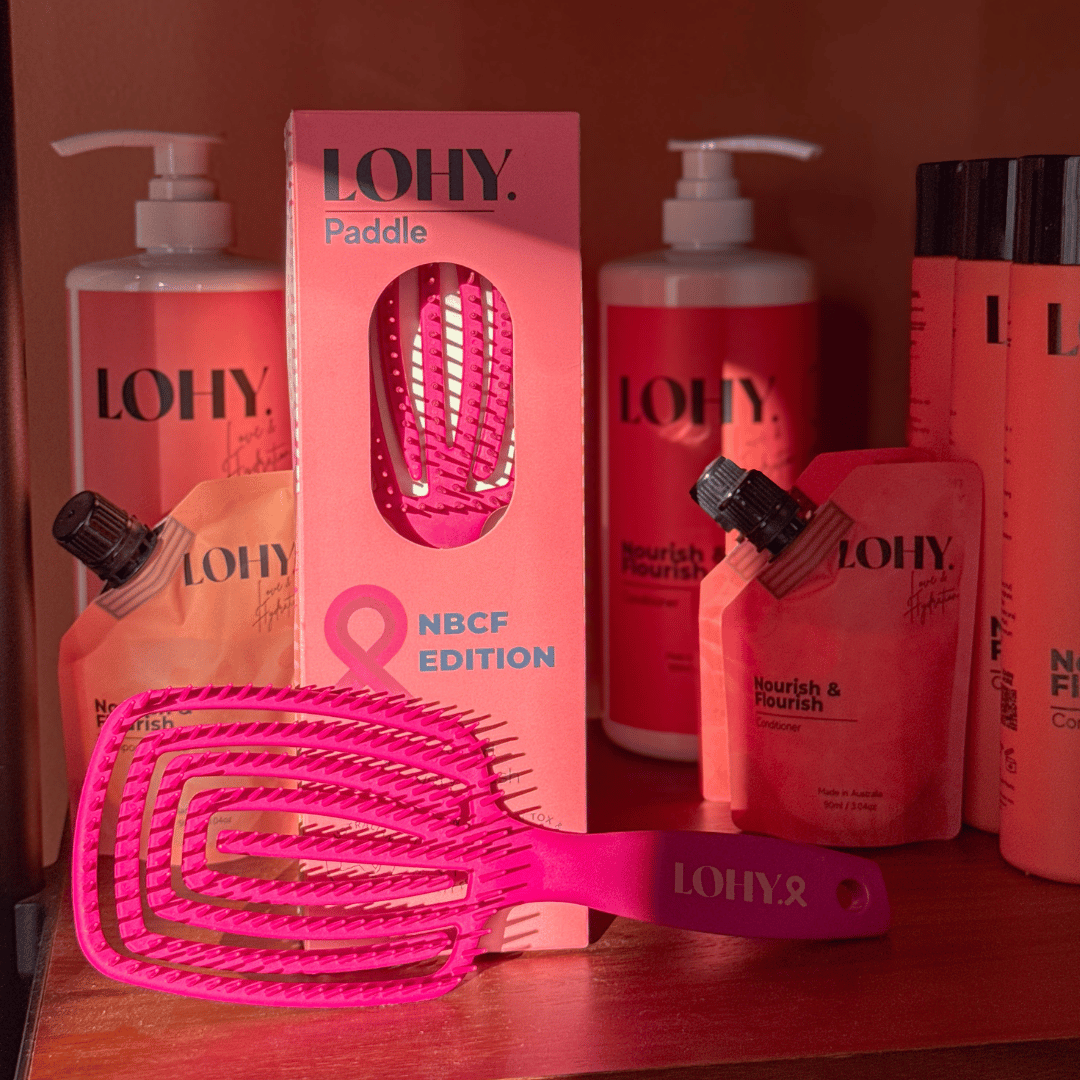 PINK LOHY. PADDLE BRUSH ON SHELF WITH SHAMPOO AND CONDITIONER