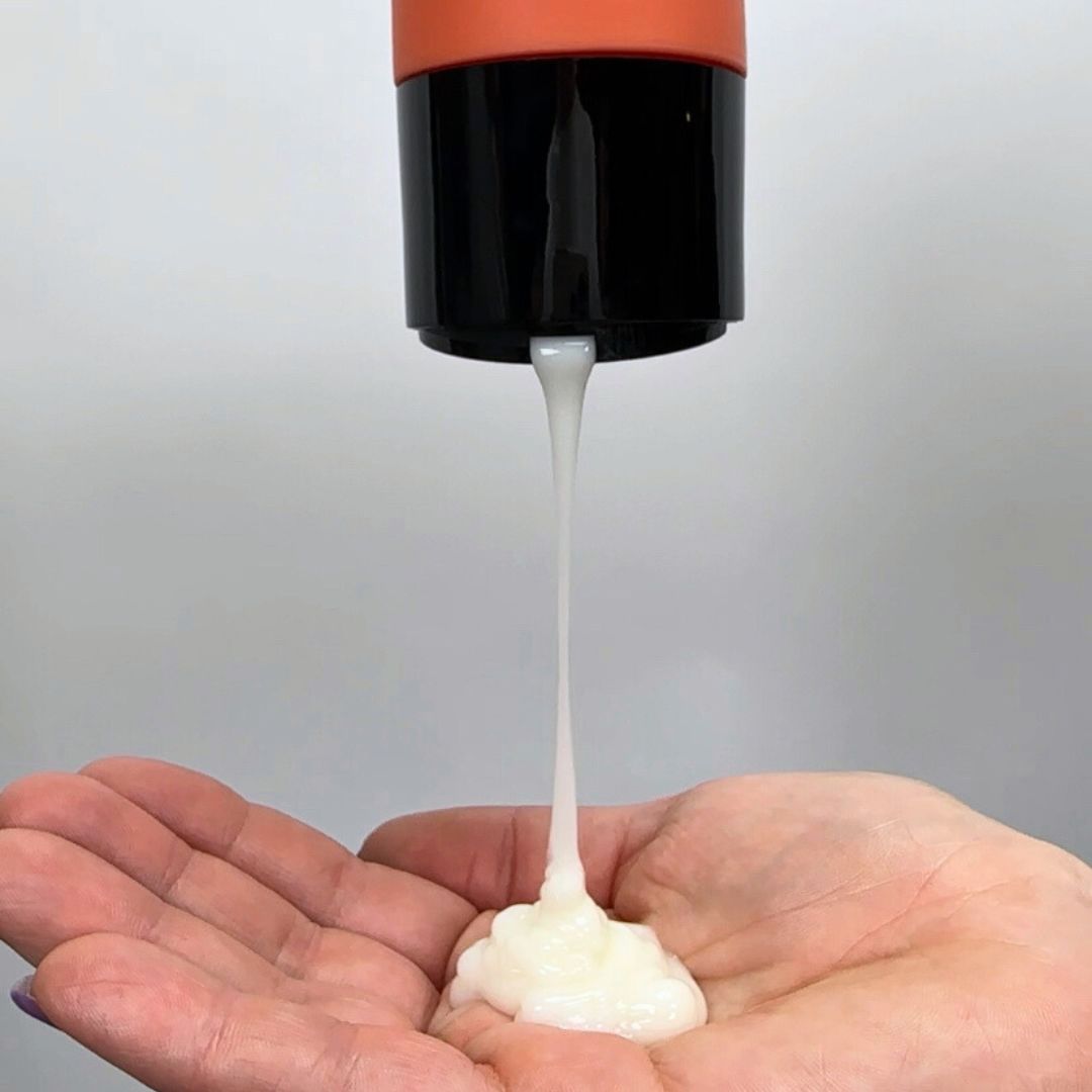 Curly hair conditioner being poured into palm of hand