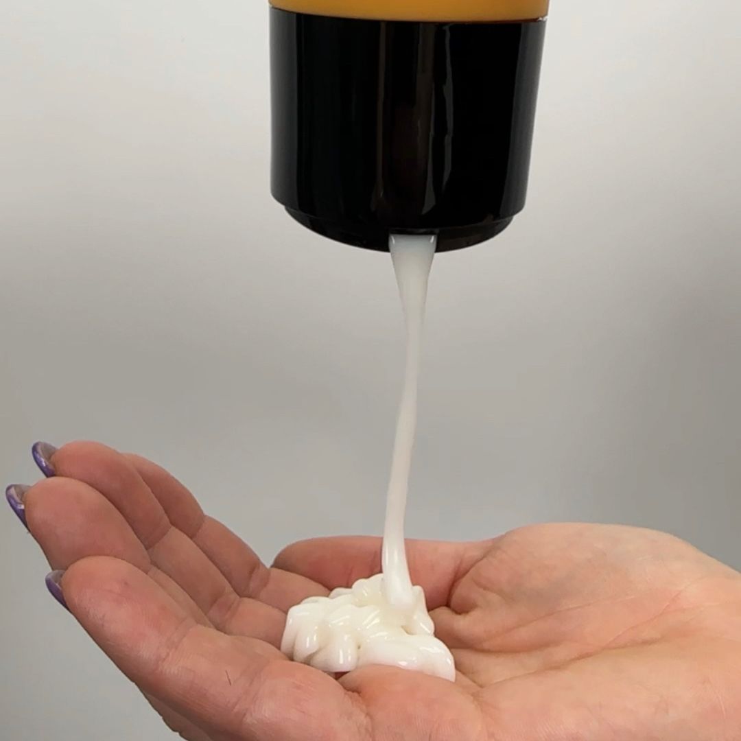 Curl cream being poured into palm of a hand