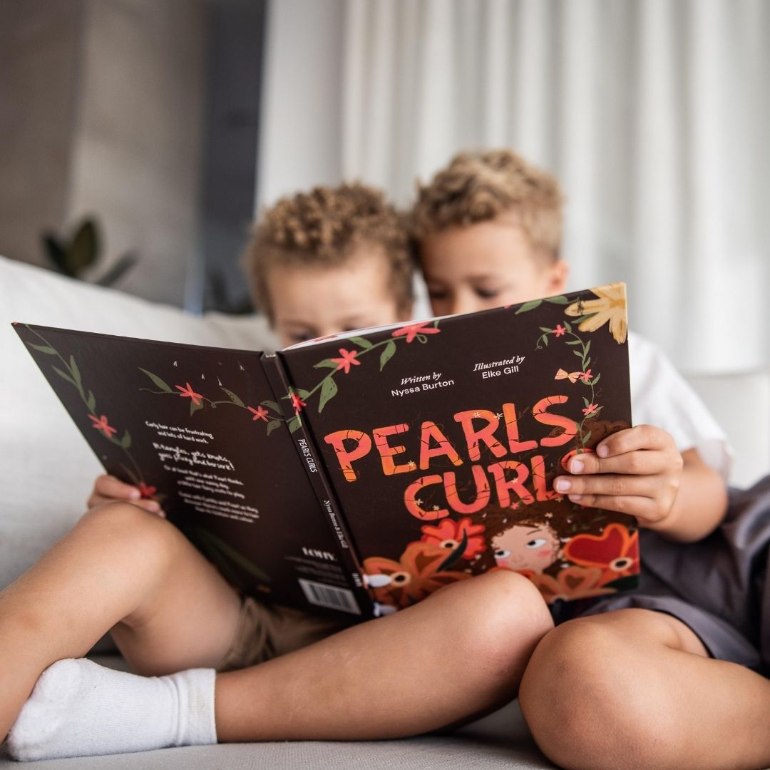Two kids reading pearls curls book together